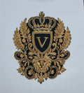 An ornate black and gold embroidered decorative emblem featuring a crown, shield with a large letter V, laurel leaves, a lion head, and scrollwork on a plain light background.